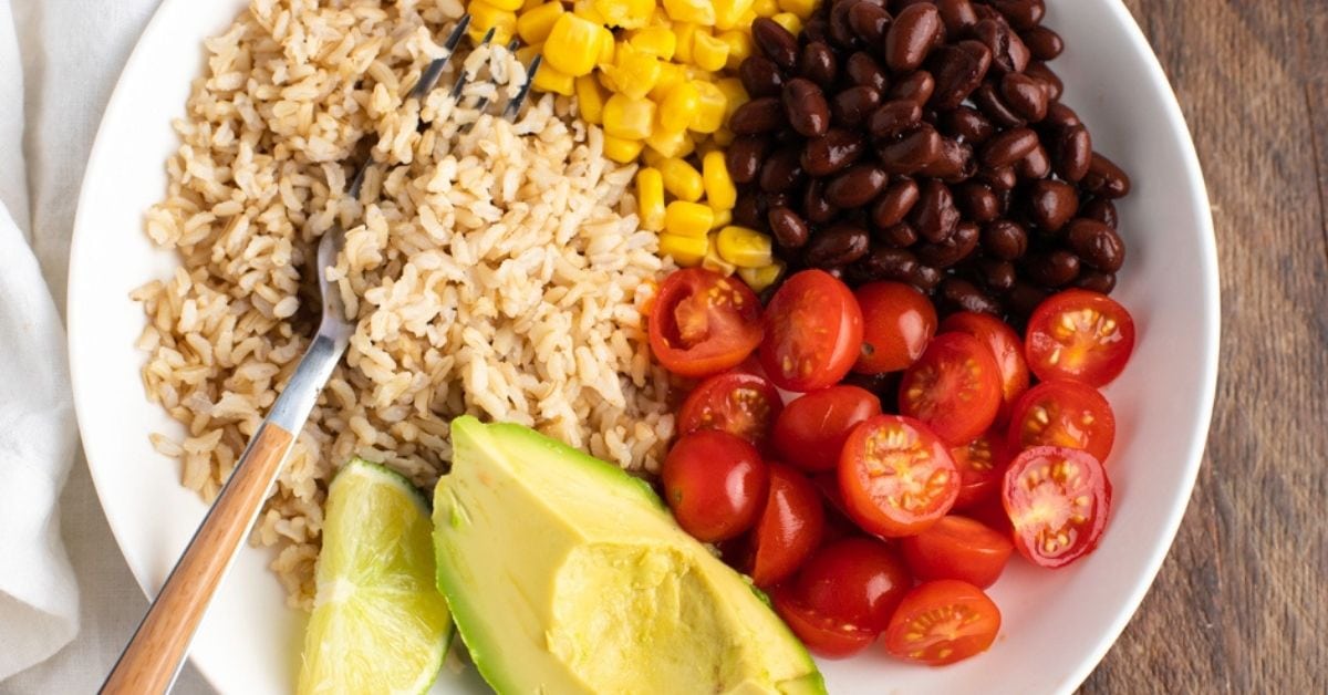 Healthy Mexican Buddha Bowl with Brown Rice, Cherry Tomatoes, Black Beans, Corn and Avocados