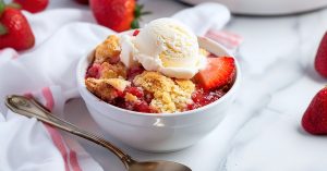 Homemade fluffy and gooey strawberry cobbler in a white bowl