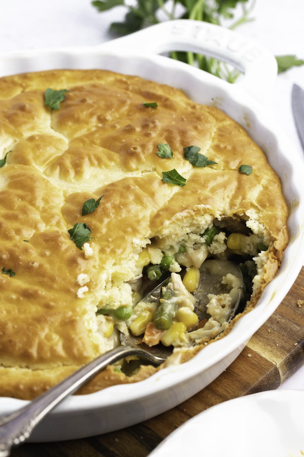 Chicken pot pie in a round casserole dish portion missing showing filling.