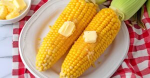 A plate of two homemade microwave corn on the cob with butter