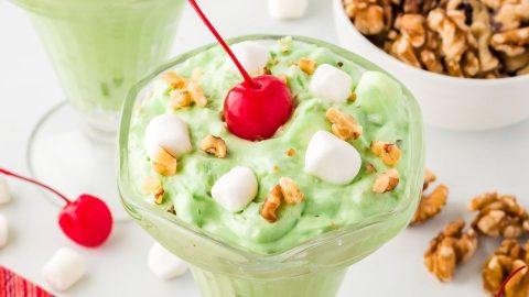 Watergate salad with cherries, mini marshmallows, chopped walnuts served in a dessert cup.