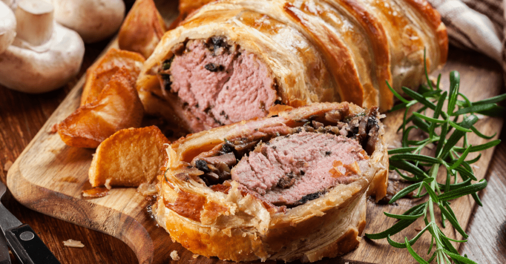 What to Serve with Beef Wellington: Beef Wellington slice on cutting board with potatoes