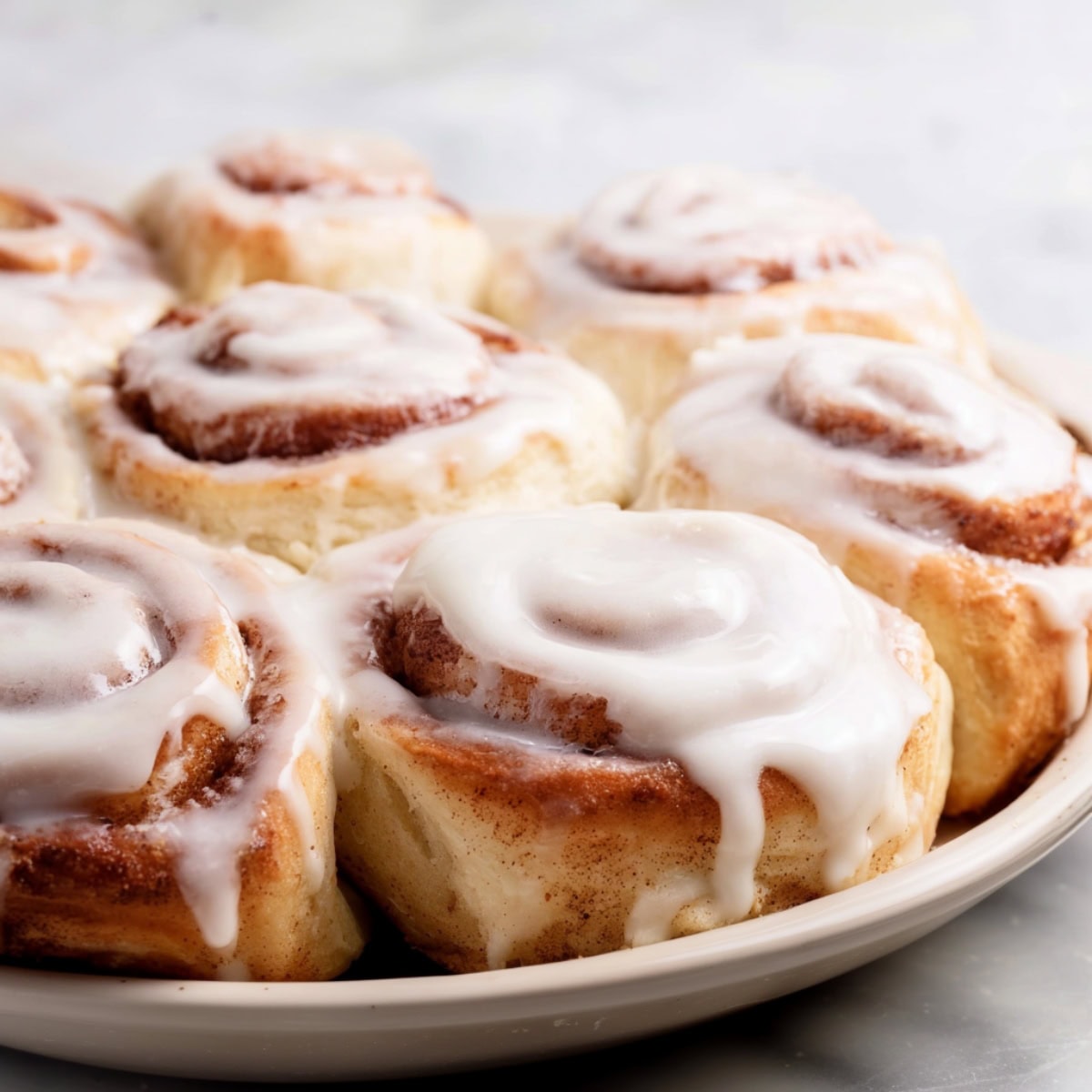 Bisquick cinnamon rolls with glaze on a white plate.