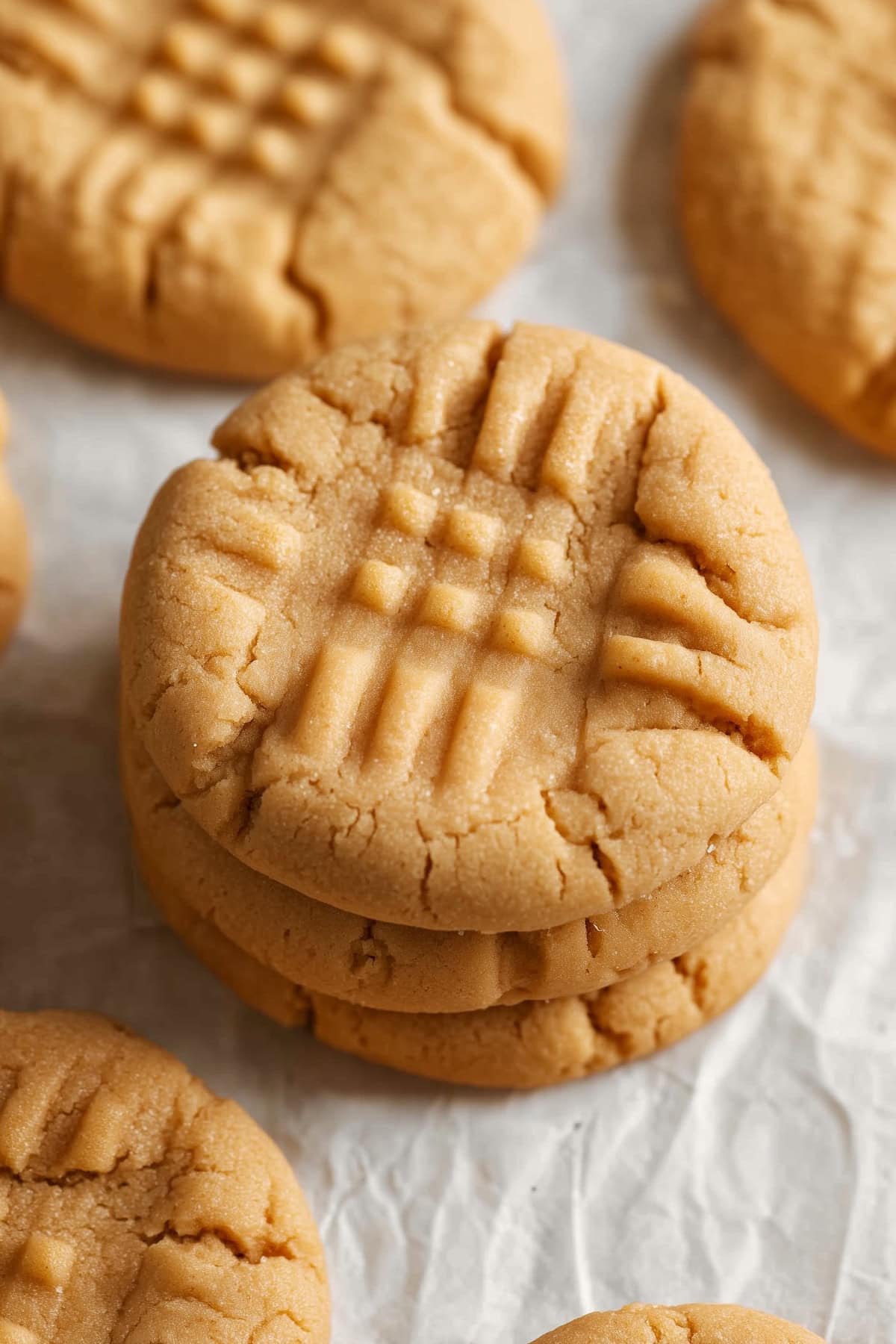 Stacked bisquick peanut butter cookies on a white parchment paper.