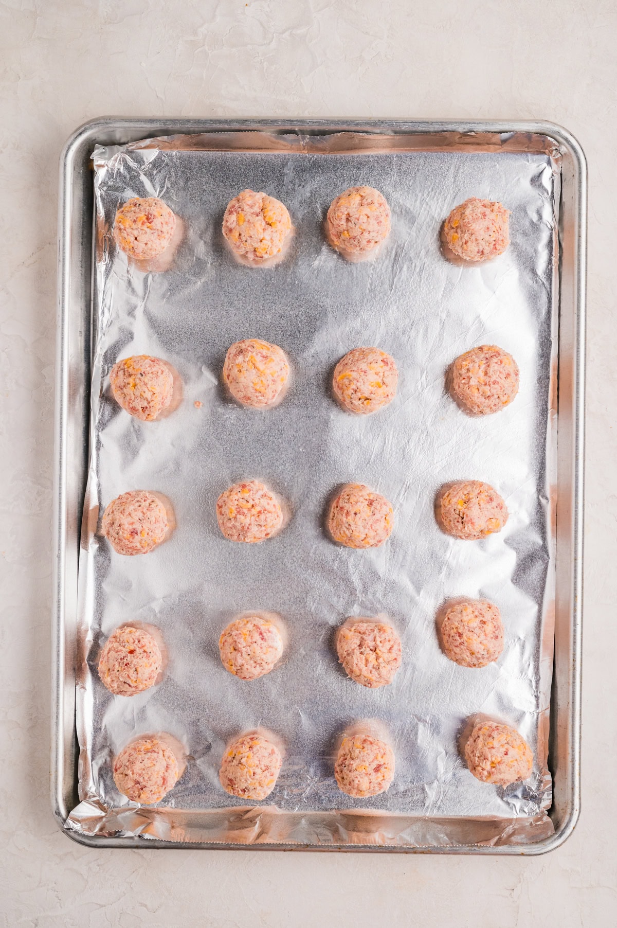 uncooked sausage balls on parchment-lined baking sheet