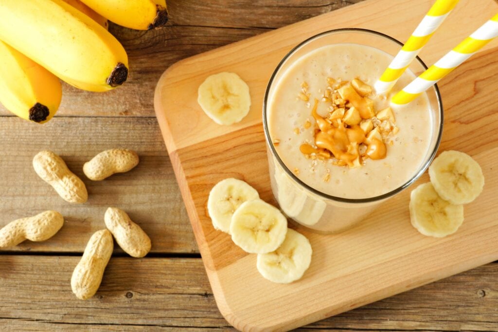 Peanut Butter Banana Smoothie on Cutting Board with sliced bananas