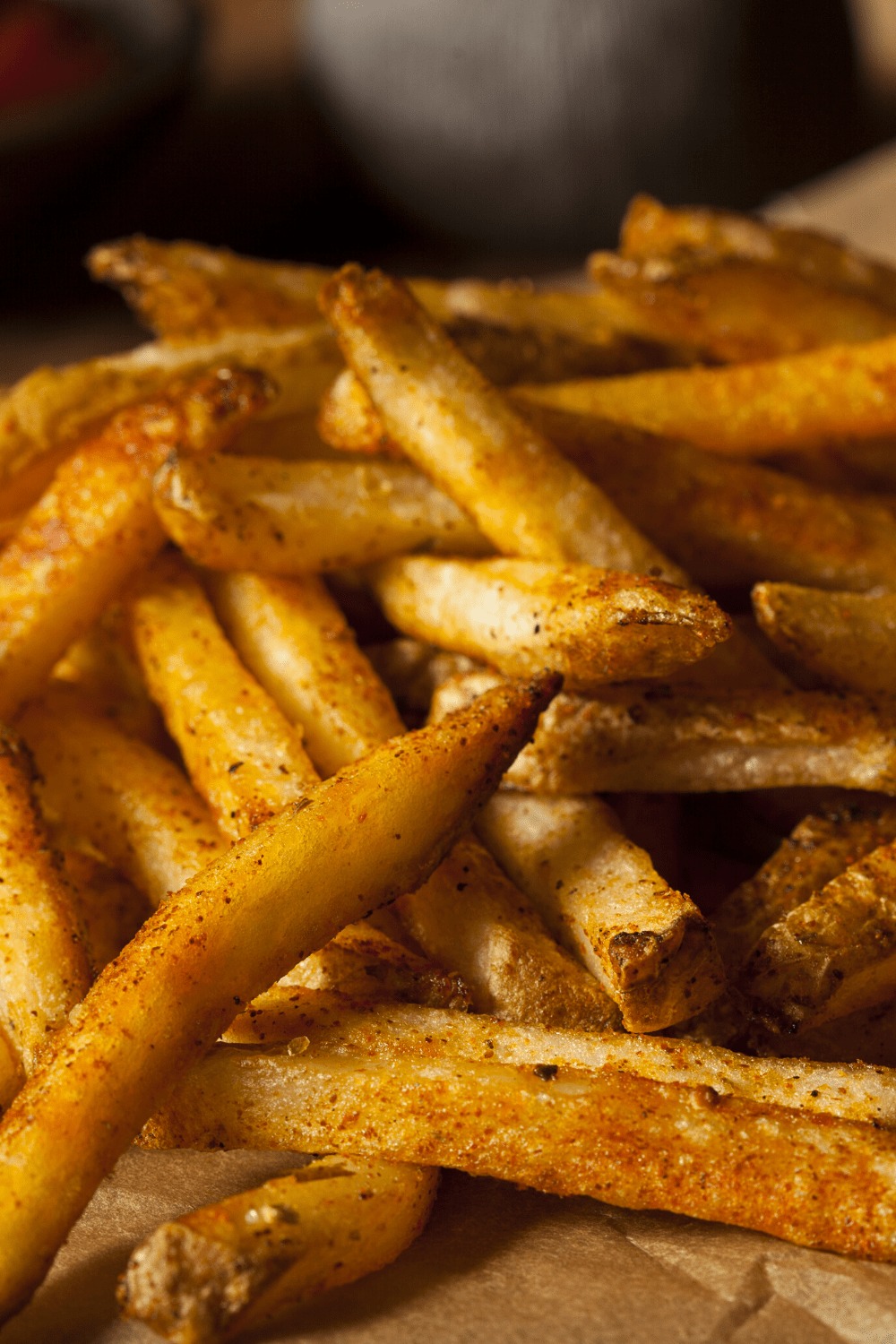 Bunch of seasoned French fries on a parchment paper.