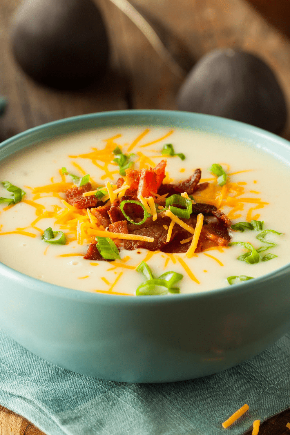 A huge bowl of Potato Soup topped with bacon, chopped onion leaves and grated cheese. 