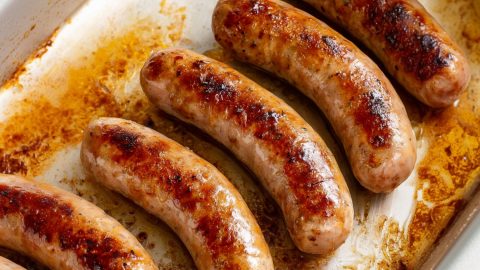 Cooked bratwurst in a baking dish, close-up.