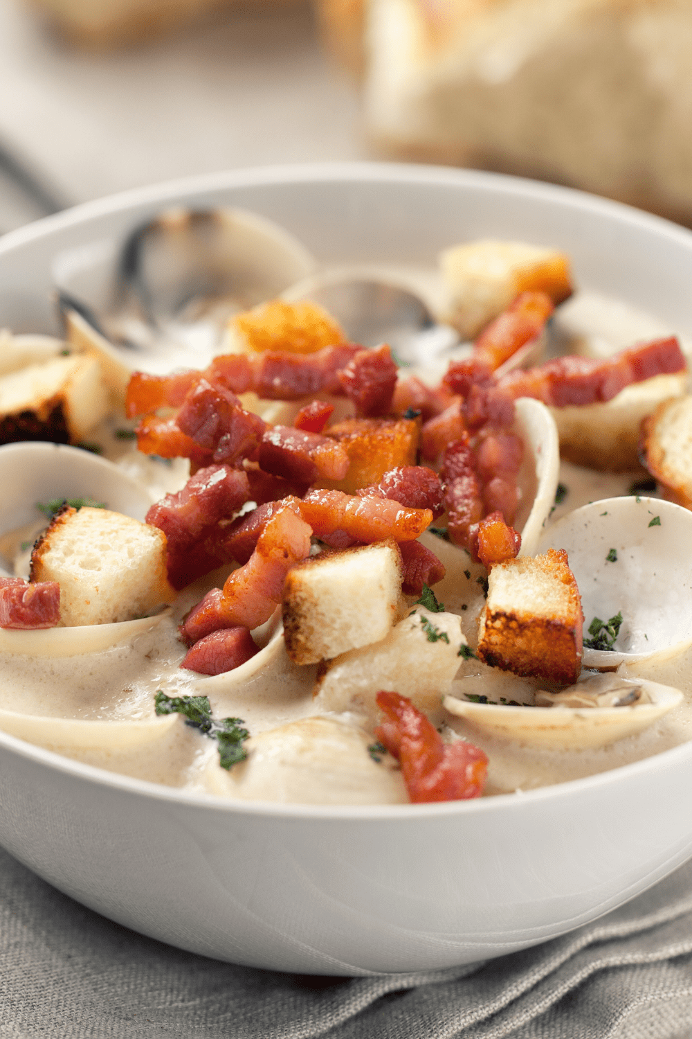 Clam Chowder with creamy soup, bacon and croutons served on a white bowl. 