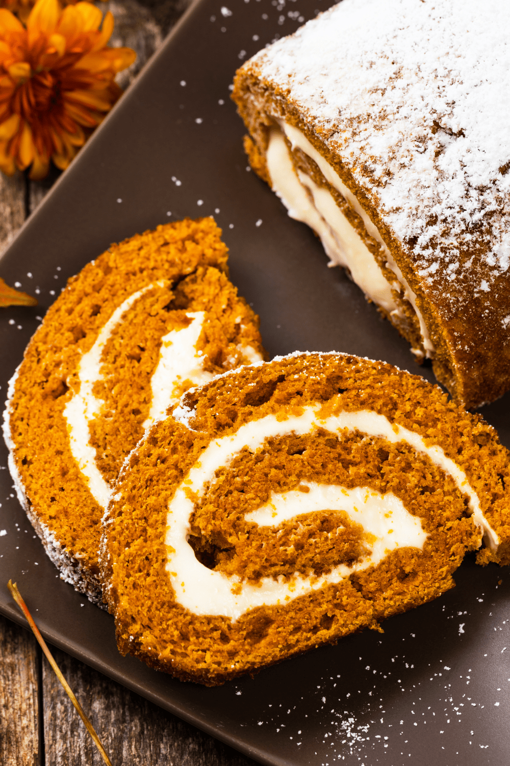 Slices of pumpkin roll with cream cheese filling served on a black plate. 