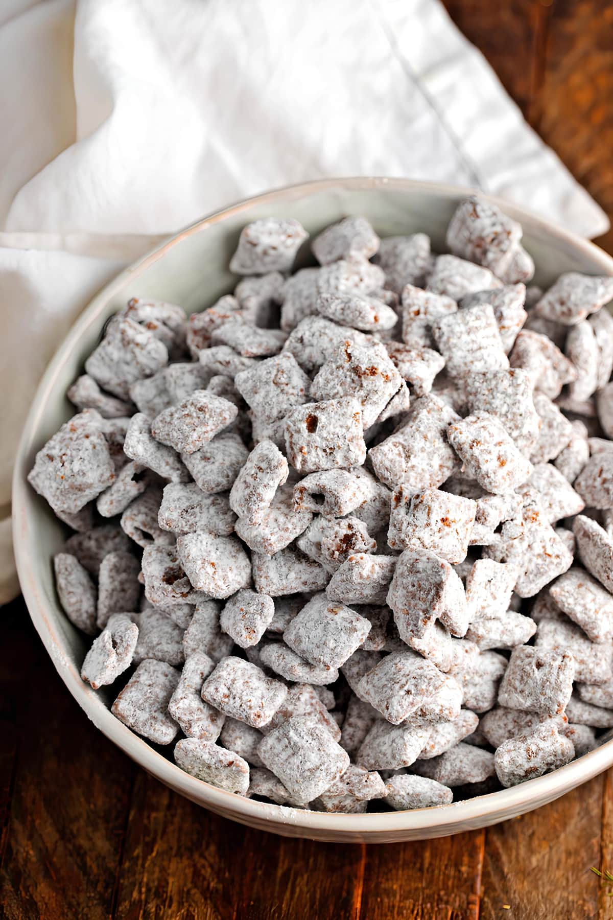 Chex coated in melted sugar and peanut butter mixture on a white bowl.