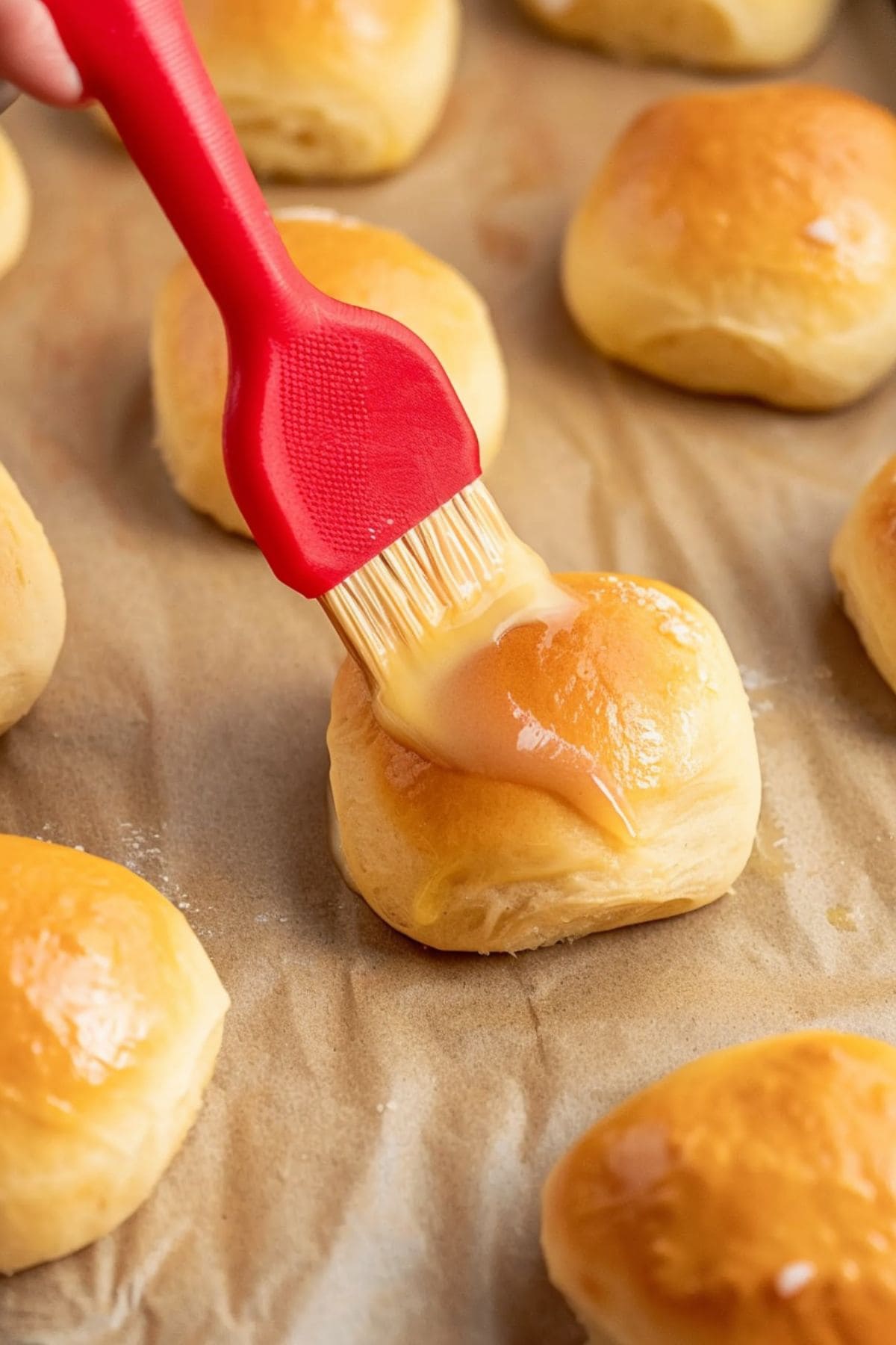 A pastry brush brushing melted butter onto freshly baked rolls. 