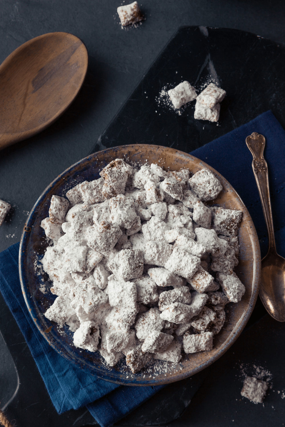 Bunch of Homemade Puppy Chow on a plate with powdered sugar
