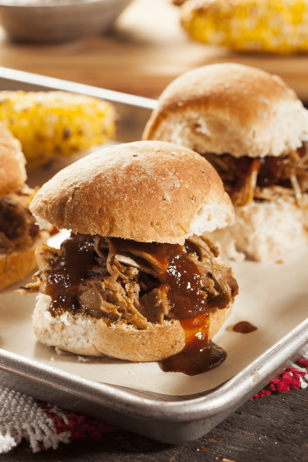 Pulled Pork Sliders with sauce dripping on a tray with parchment paper