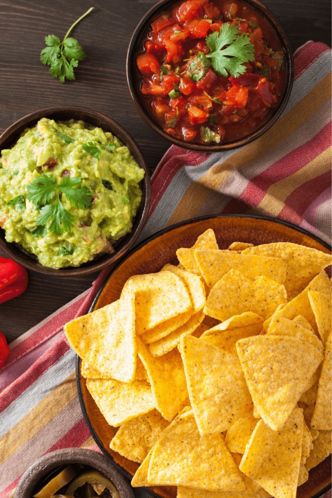 Bowl of Tortilla chips with guacamole and salsa on the side