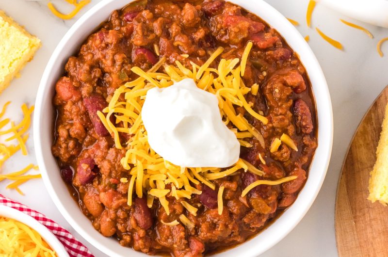 Wendy's Chili copycat recipe with beans, ground beef, cheese and sour cream in a white bowl