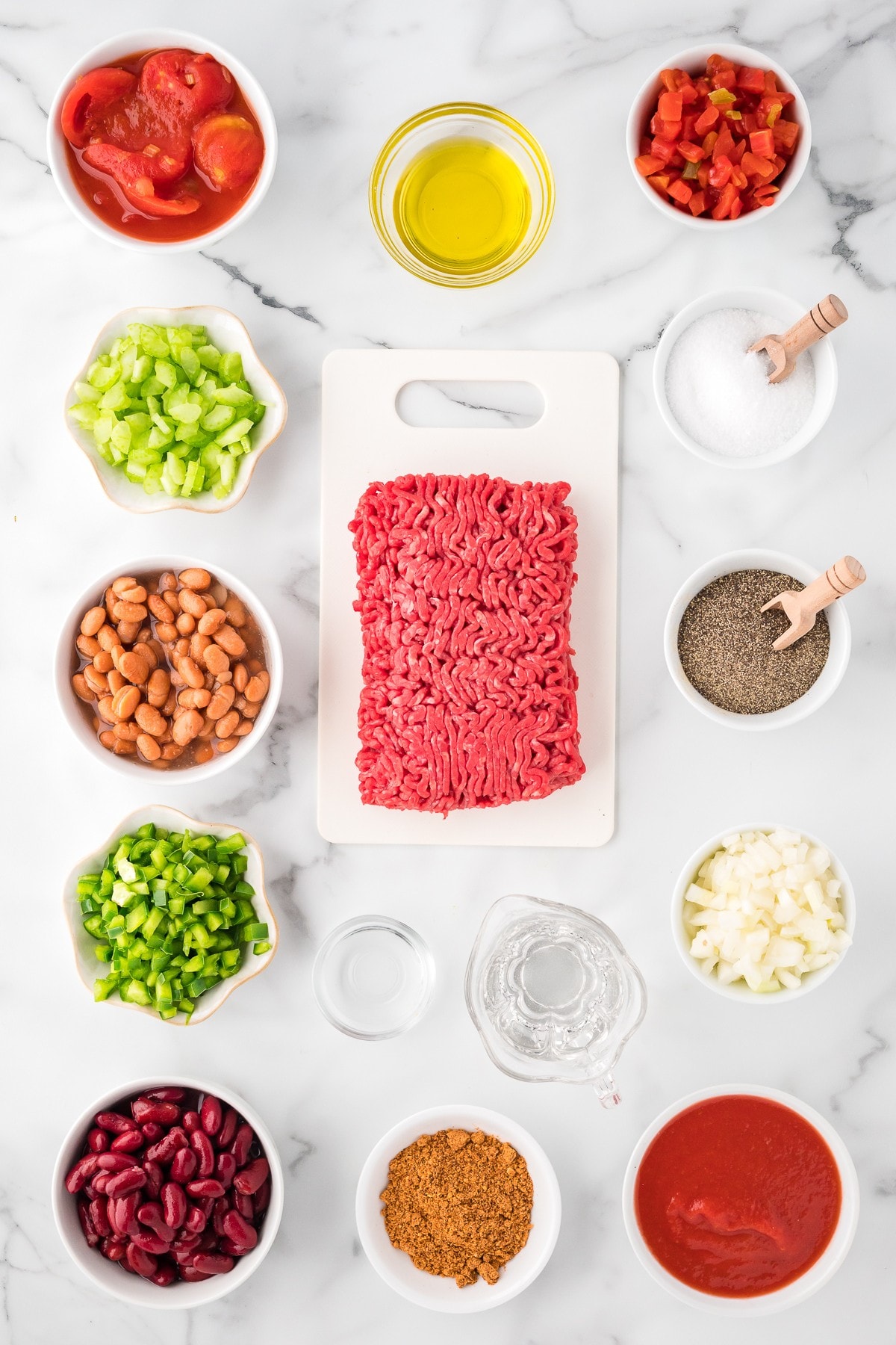 Wendy's Chili Ingredients: olive oil, ground beef, green bell peppers, celery, onion, stewed tomatoes, diced tomatoes with green chilis, kidney beans, pinto beans, salt, pepper, and chili spice mix - top view