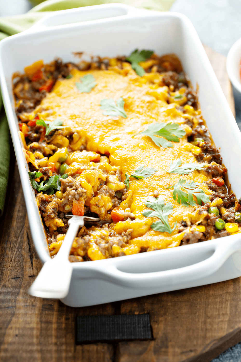 Ground beef casserole with corn and peas with melted cheese on top.