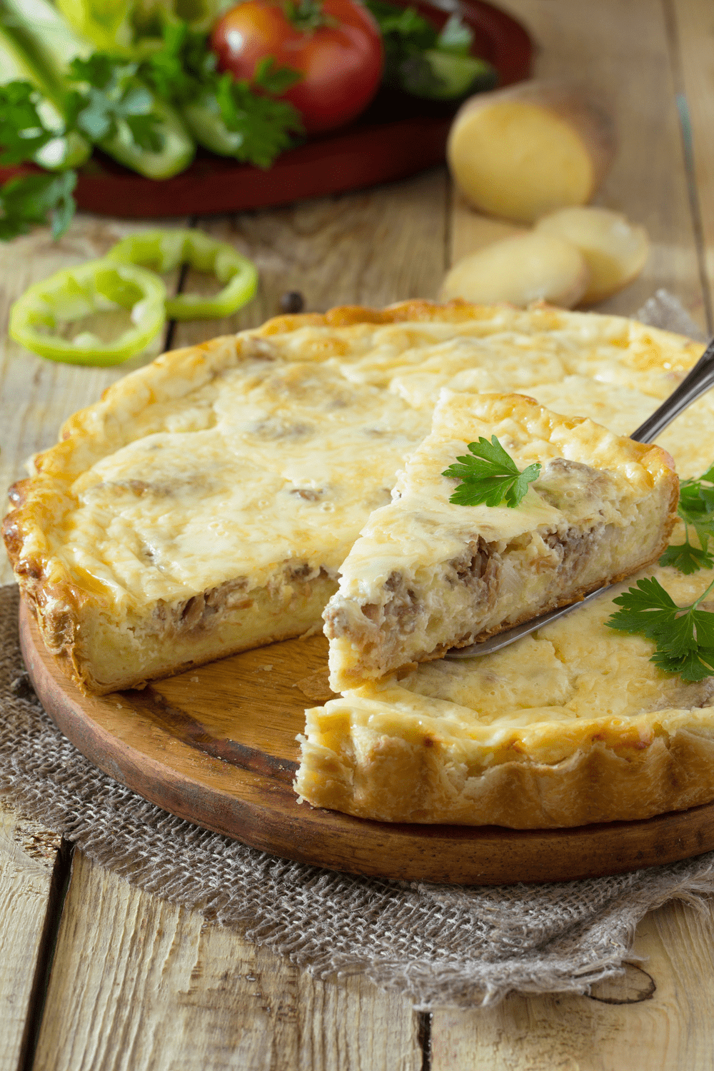 Pie with ground beef garnished with celery leaves served on a wooden cutting board