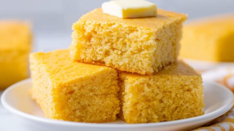 Three yellow golden moist cornbread, stacked in a white plate.
