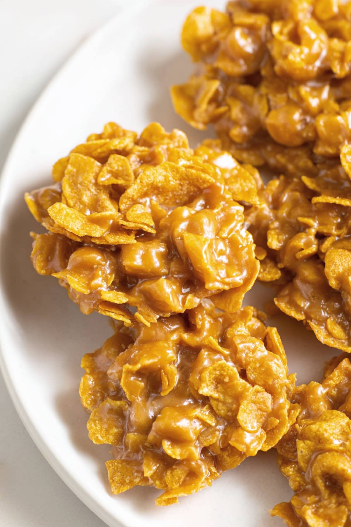 Top view of peanut butter cornflake cookies in a white plate on a white marble table.