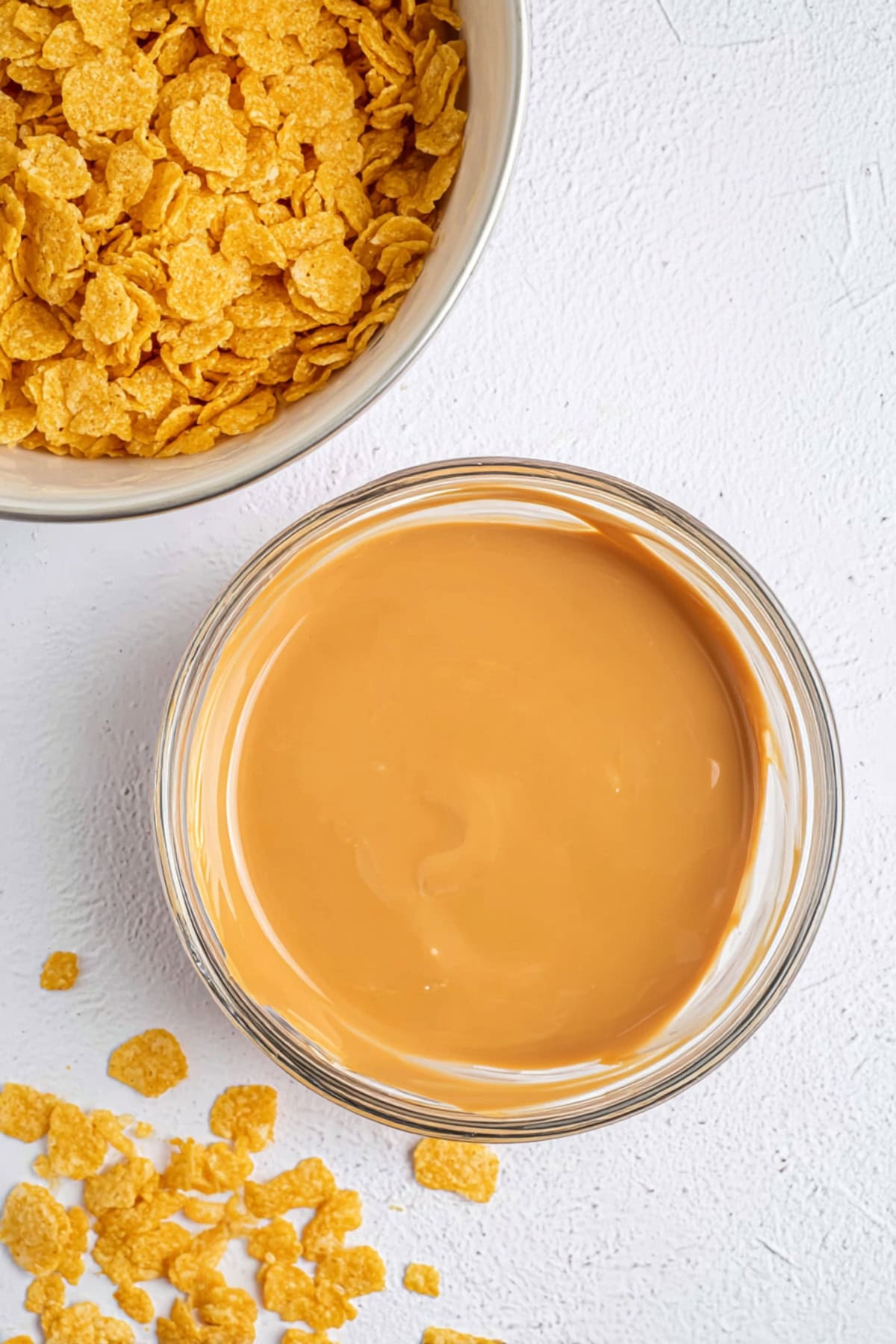 Cornflakes and melted peanut butter in bowls.