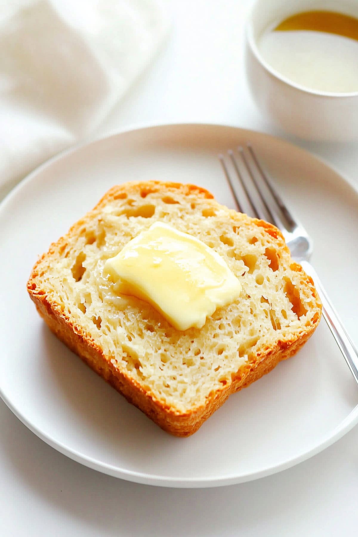 Slice of honey beer bread topped with butter, with a cup of tea on the side - 7