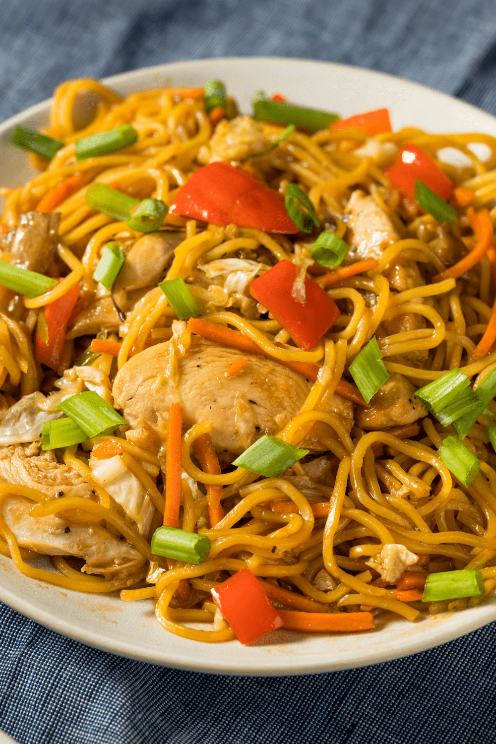 Yakisoba noodles with thick sauce to coat the noodles, chicken, and veggies served on a plate.