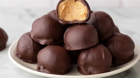 Stacked chocolate-covered peanut butter balls in a white plate.