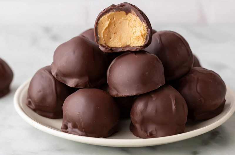 Stacked chocolate-covered peanut butter balls in a white plate.