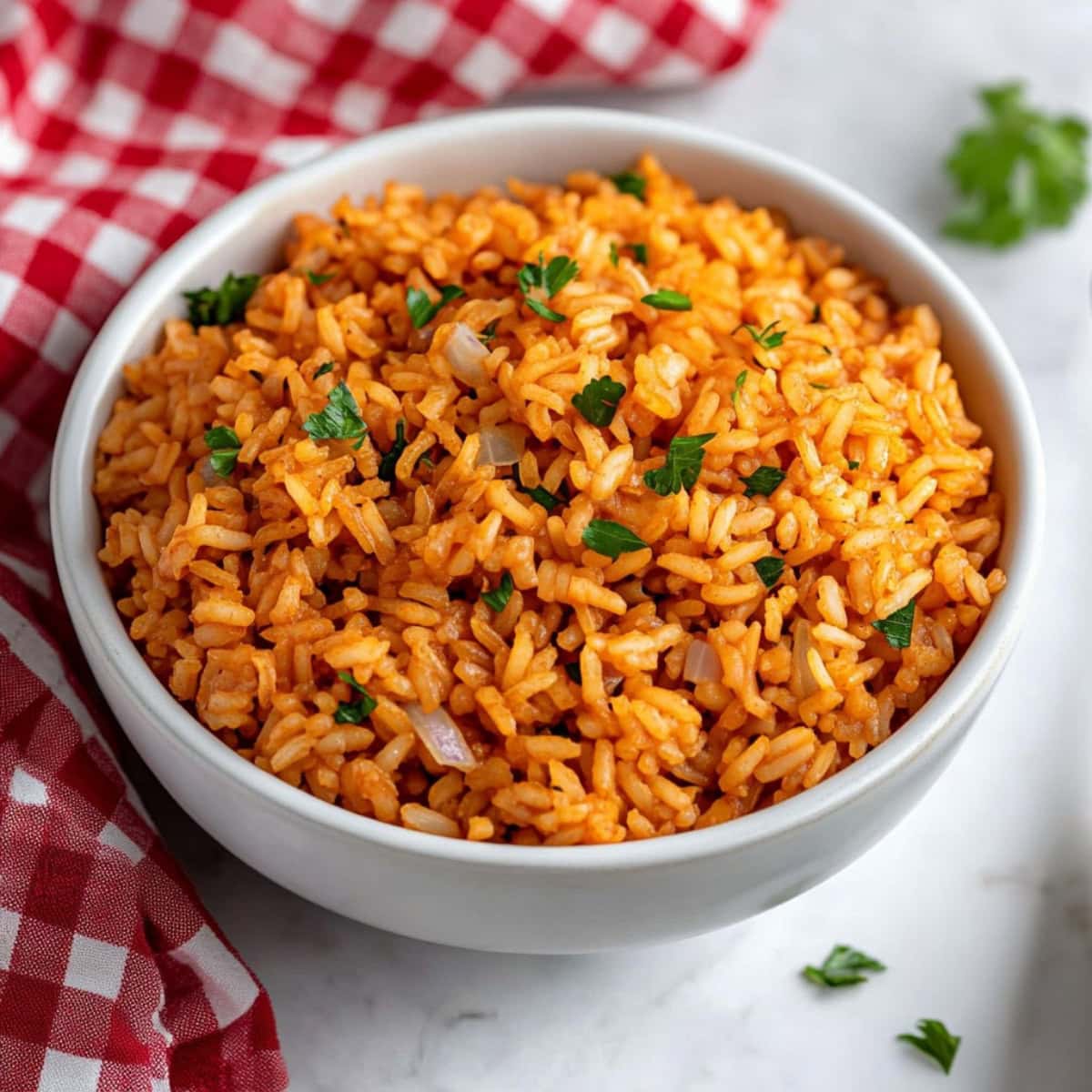 Seasoned Rice garnished with fresh parsley in a white bowl on a marble table with a kitchen cloth on the side