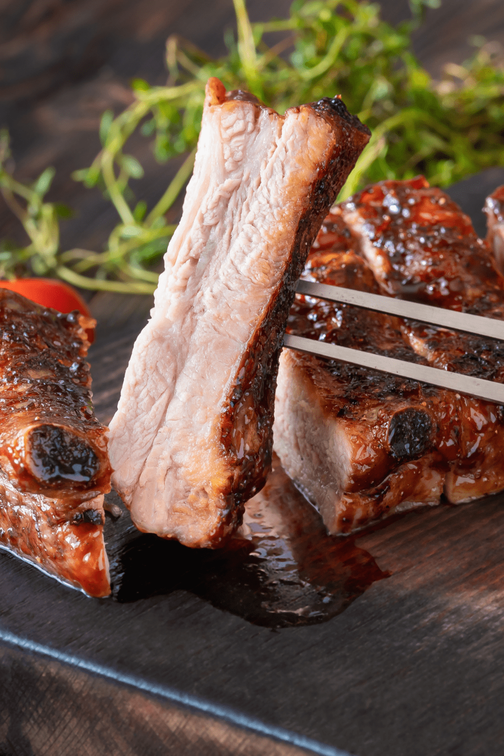 Easy Air Fryer Ribs featuring Air Fryer BBQ Pork Ribs Cut Into Slices on a Cutting Board, One Piece Picked Up with a Large Meat Fork
