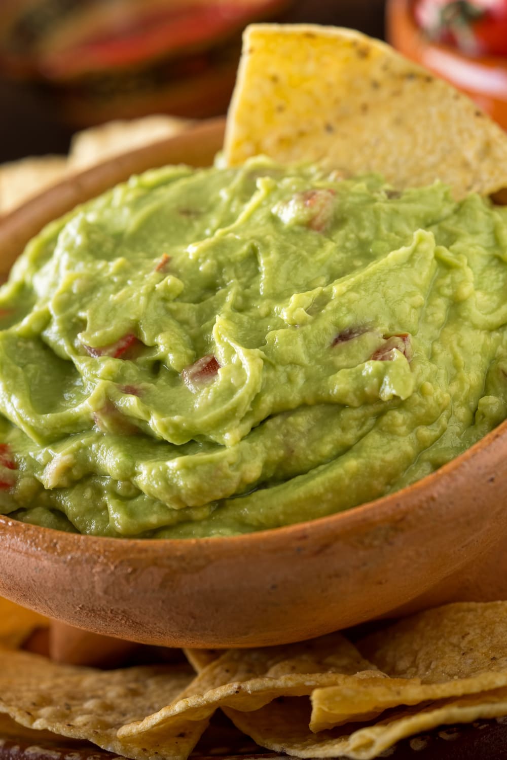 Chipotle Guacamole dip on a wooden bowl served with nachos. 