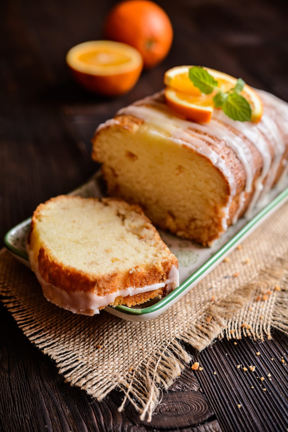 Sliced orange loaf cake drizzled with vanilla icing on top.