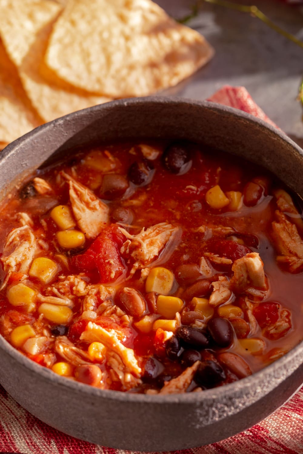 Chicken Tortilla Soup in a pot with red tomato sauce, corn, beans and meat. 