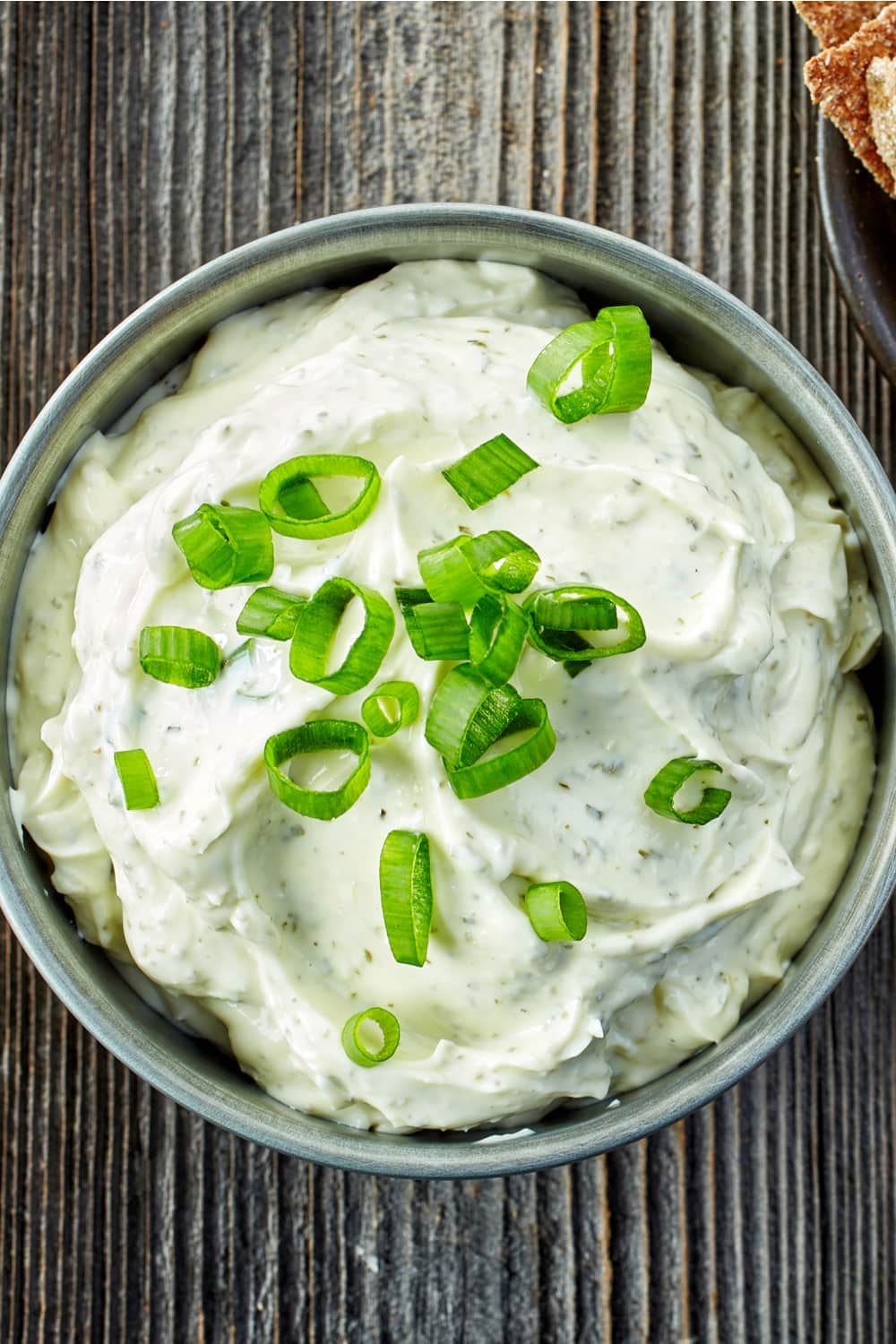 Bowl of Clam Dip garnished with green onions made with cream cheese, garlic, Worcester sauce, and lemon juice.