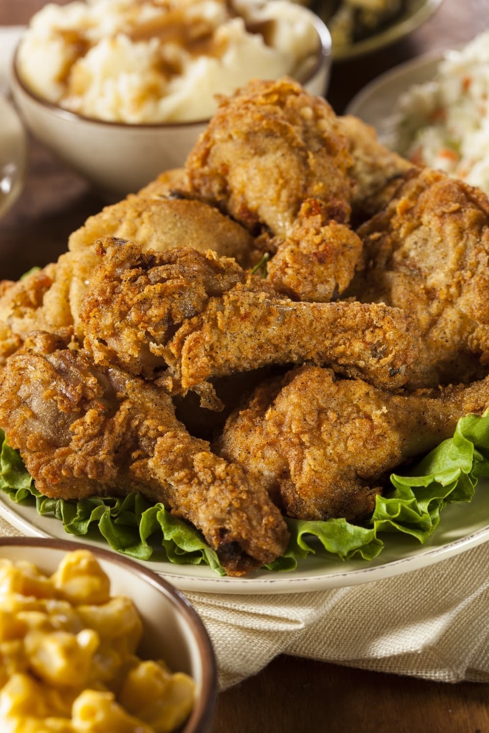 Bunch of fried chicken in bowl layered with fresh lettuce. 