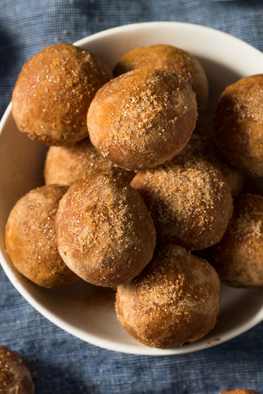Bunch of donut balls on a bowl coated with sugar.