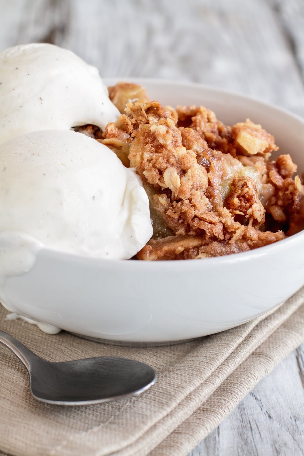 Homemade Apple Brown Betty served with a scoop of vanilla ice cream on  a white bowl. 