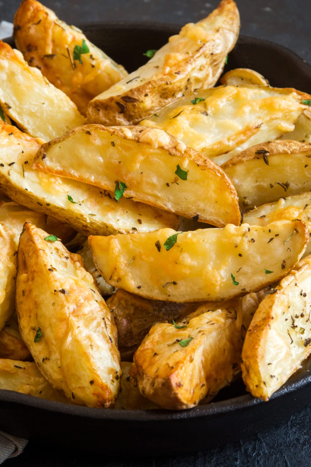 Bunch of baked potato wedges on a skillet. 