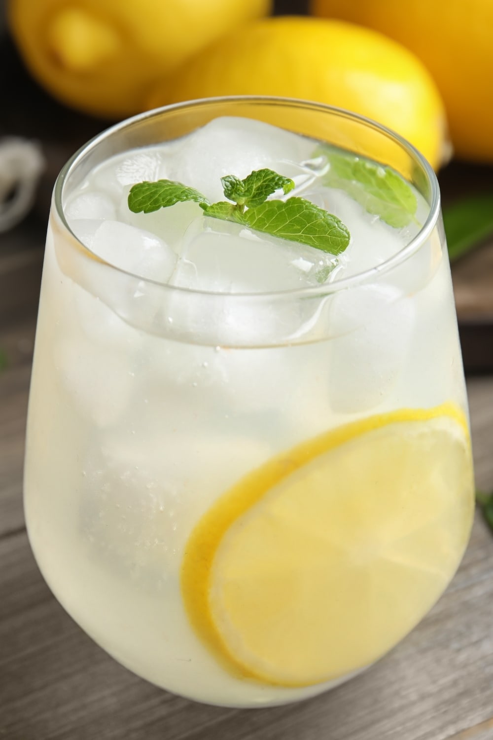 Glass of lemonade with ice. slice lemon and mint leaves on top