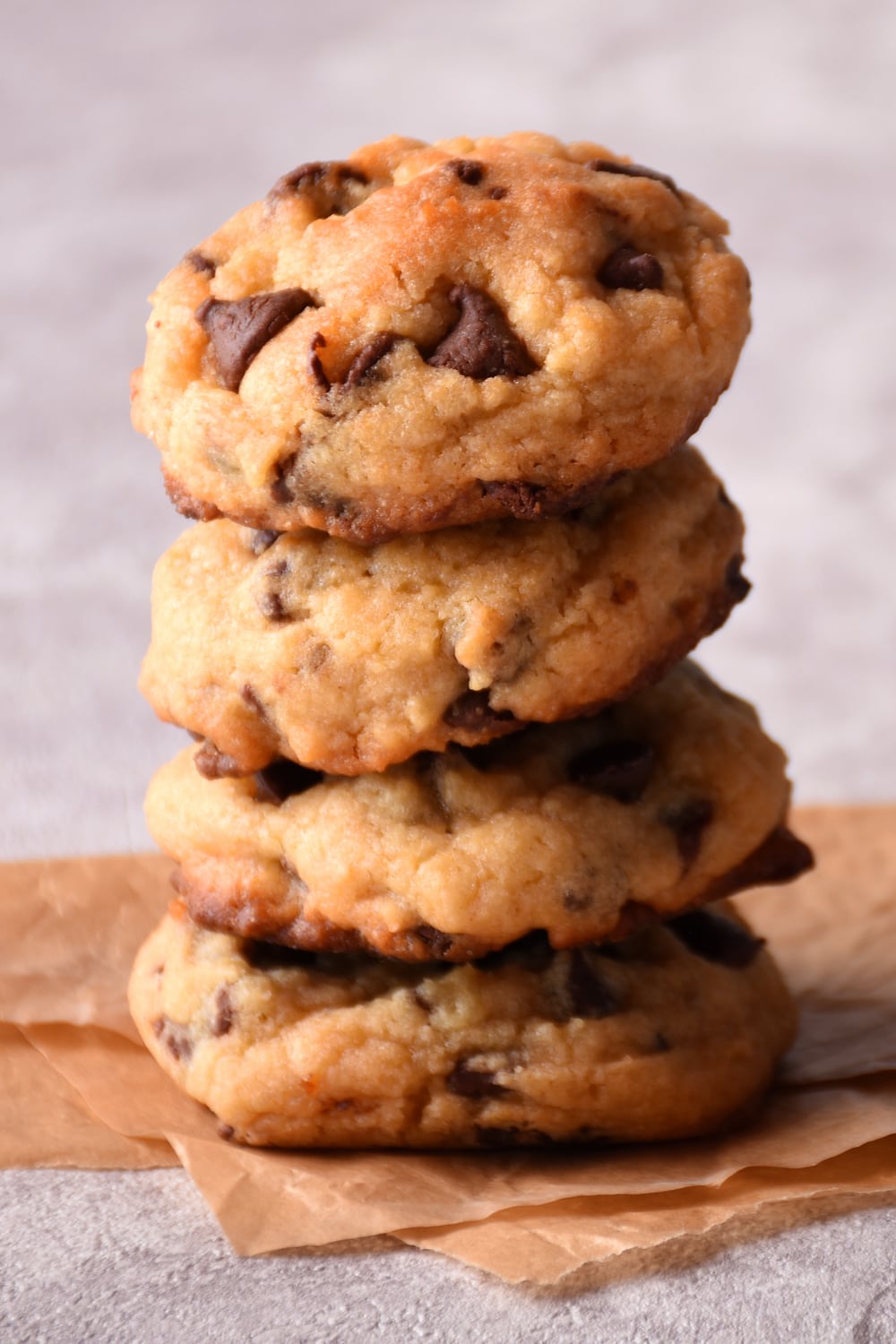 Stack of chocolate chip cookies on top of parchment paper.