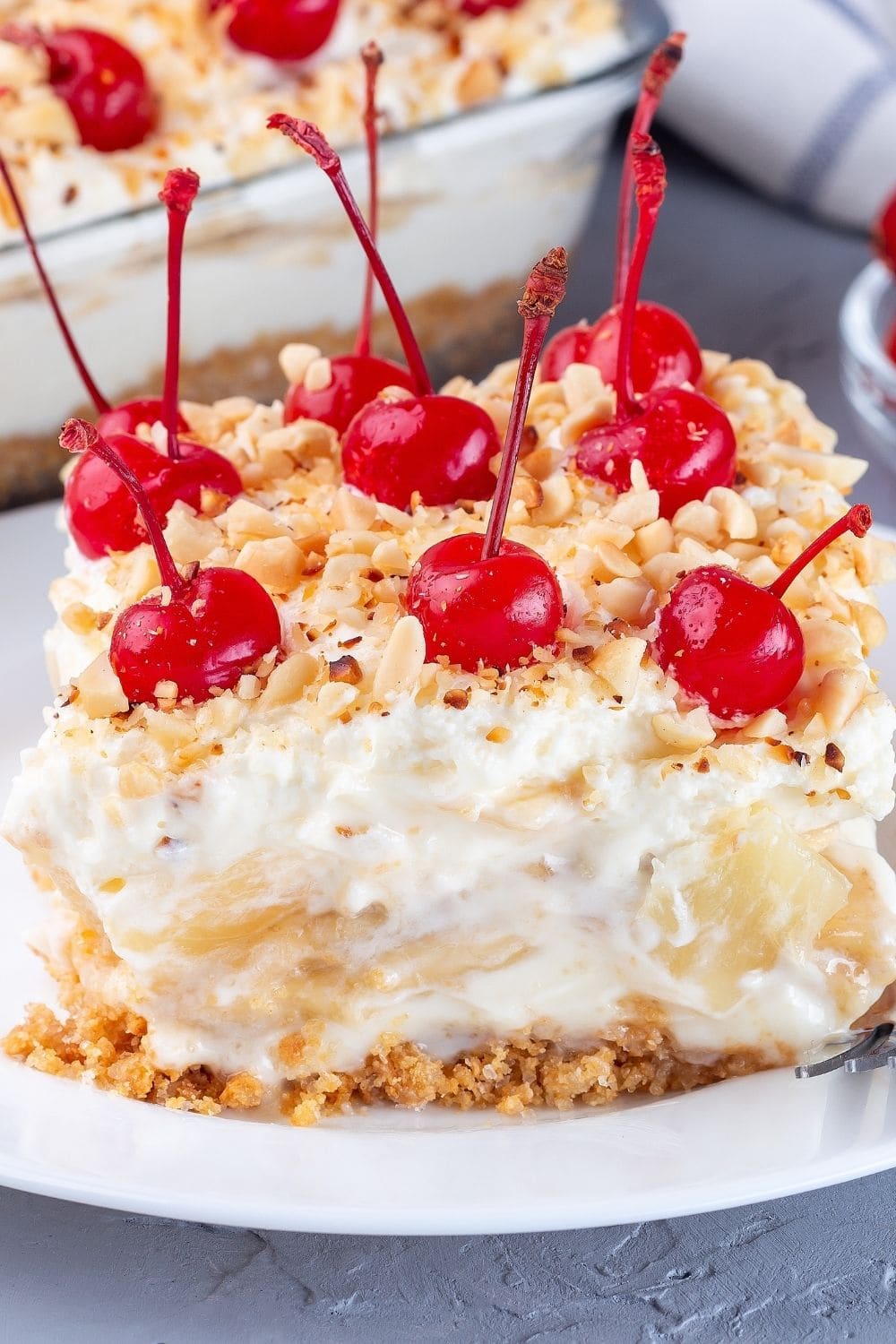 Banana Split Cake Topped With Crushed Nuts and Fresh Red Cherries