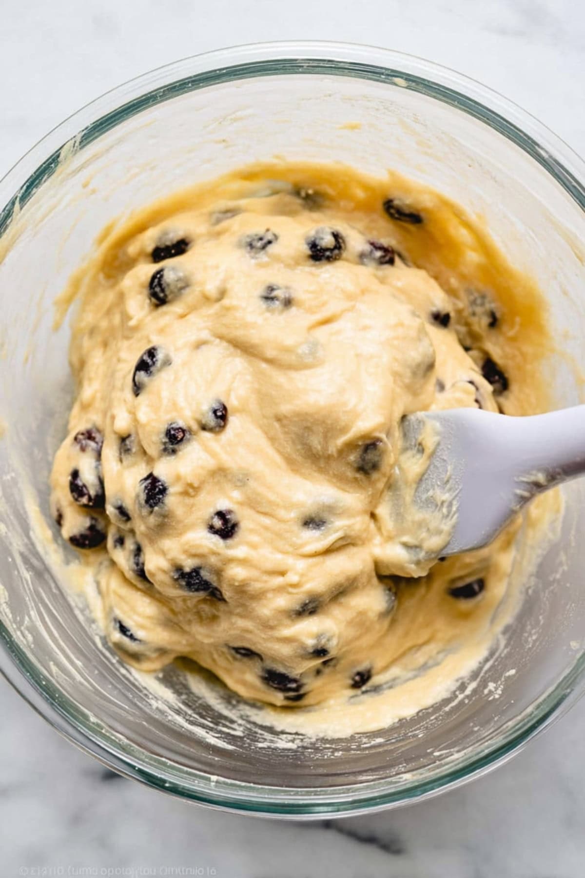 Blueberry muffins batter in a glass bowl.