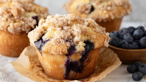 Three blueberry muffins in a brown parchment paper.