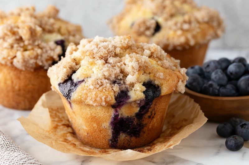 Three blueberry muffins in a brown parchment paper.