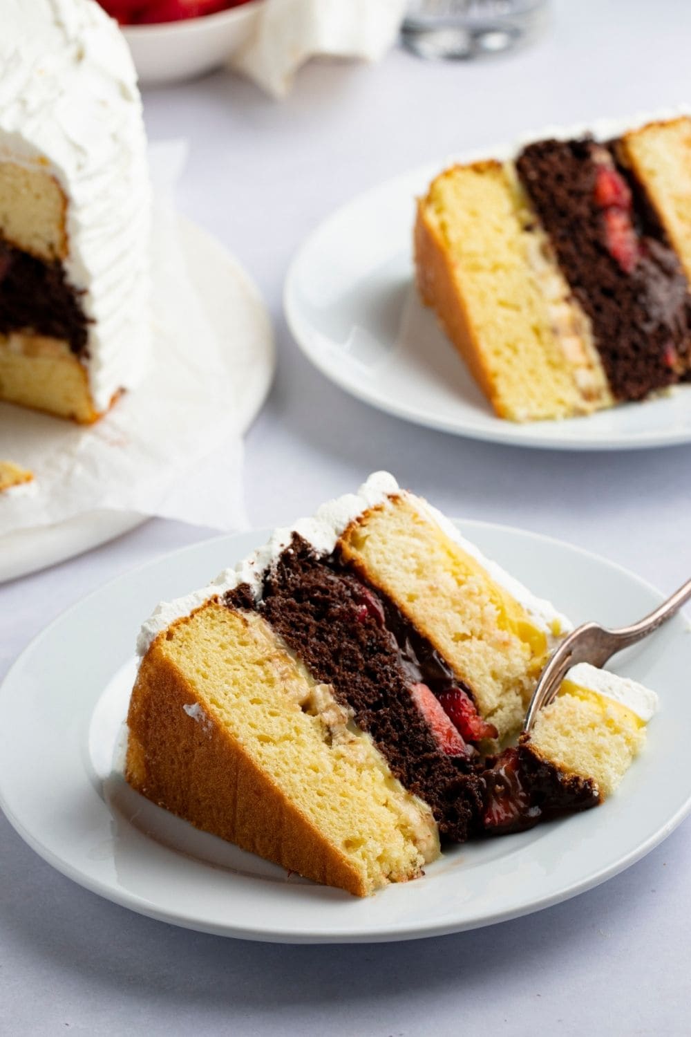 A slice of butter and chocolate layered cake with fruit filling covered with vanilla frosting.