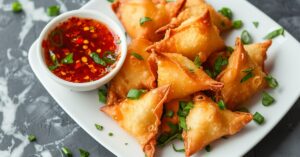 Crispy homemade air fryer crab rangoon with chili sauce in a white plate