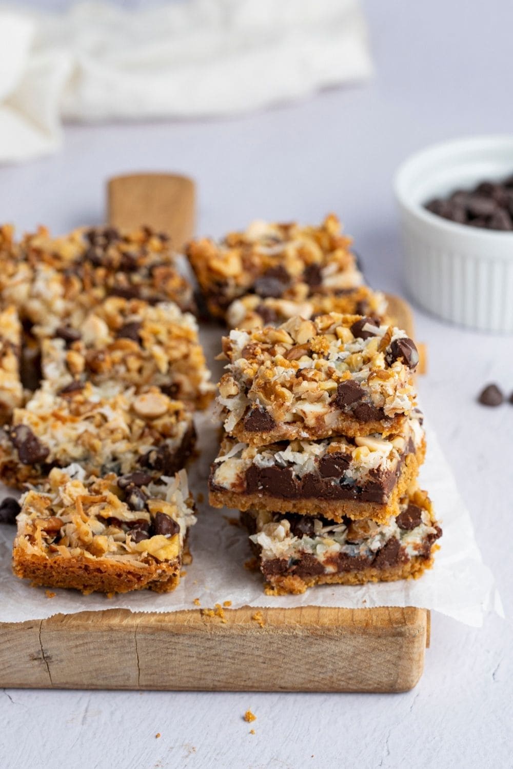 Homemade Hello Dolly Bars stacked on a chopping board